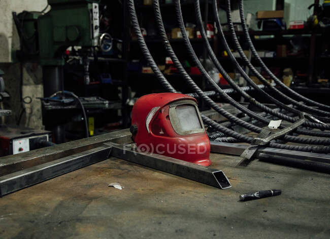 Metalltisch mit Schweißmaske in der Nähe von stationärer Spule mit elektrischem Draht in professioneller Garage — Stockfoto