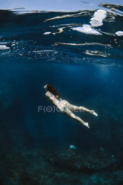 Turista femenina en traje de baño nadando en un mar limpio y transparente durante las vacaciones en un soleado resort tropical - foto de stock