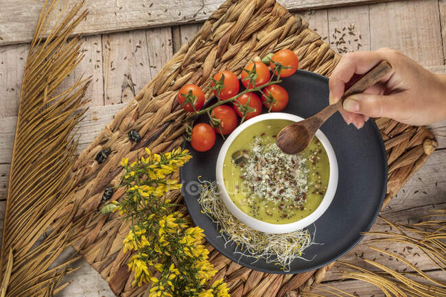 Вид сверху на анонимного шеф-повара с миской вкусного вегетарианского кремового супа с дроблеными фисташками и приправами сверху — стоковое фото