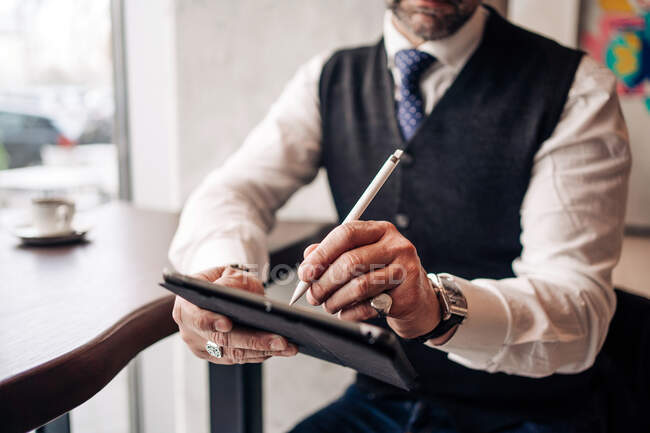 Vista da colheita anônimo executivo masculino usando stylus e celular na mesa de lanchonete — Fotografia de Stock