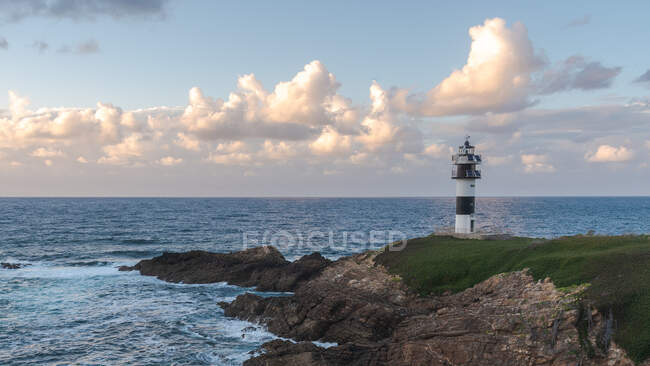 Paysage pittoresque de rivage herbeux avec phare placé près de l'océan bleu à Faro Illa Pancha en Galice en Espagne pendant la journée — Photo de stock