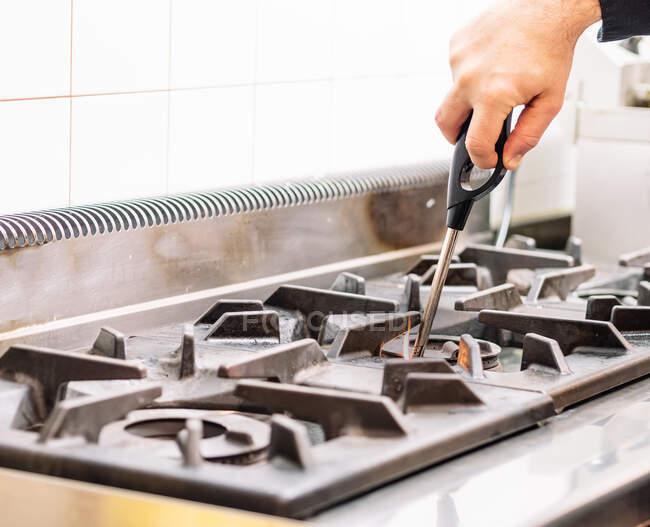 Анонімний шеф-кухар горить газову плиту з запальничкою перед приготуванням на кухні в ресторані — стокове фото