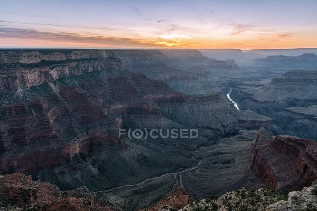 From above of picturesque landscape of rough rocky formations and river placed in Grand Canyon National Park in Arizona in United States under colorful sky at sunrise — Stock Photo
