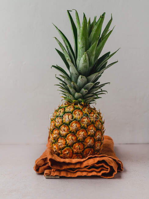 Ananas sucré entier mûr placé sur la serviette sur la table dans la cuisine — Photo de stock