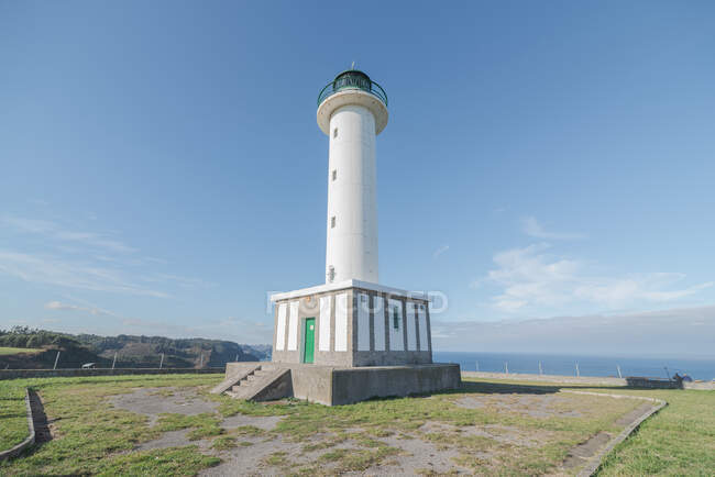 Route asphaltée menant au phare blanc placé à Faro de Lastres dans les Asturies en Espagne sous un ciel bleu sans nuages en journée — Photo de stock