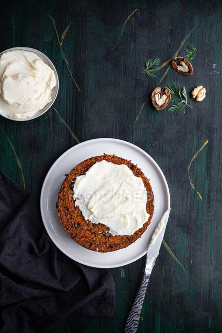 Vue aérienne du délicieux biscuit à gâteau mou sur plaque avec crème tartinée et demi-noix sur la table — Photo de stock
