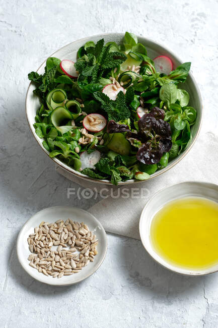 Vista superior da salada de legumes frescos e saudáveis na tigela servida na mesa com azeite e sementes de girassol — Fotografia de Stock