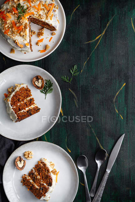 Top view of yummy cake with cream cheese served on plates with fresh carrot slices and walnuts — Stock Photo