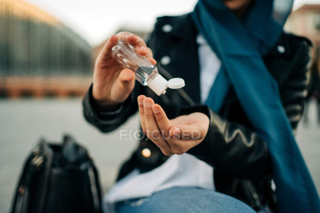 Cultive fêmea muçulmana irreconhecível no hijab aplicando desinfetante antibacteriano em mãos na rua da cidade durante a pandemia de coronavírus — Fotografia de Stock