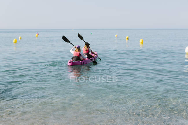 Back view anonymous people with paddles floating on kayak on azure rippling sea on sunny day in Malaga Spain — Stock Photo