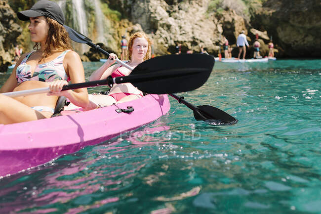 Viajantes com pás flutuando na água do mar turquesa perto da costa rochosa no dia ensolarado em Málaga Espanha — Fotografia de Stock