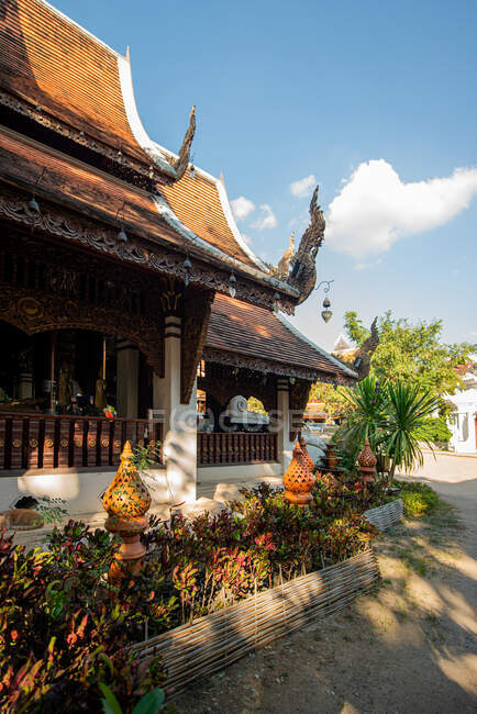 Santuário oriental envelhecido exterior contra plantas exóticas sob céu azul nublado na Tailândia no dia ensolarado — Fotografia de Stock