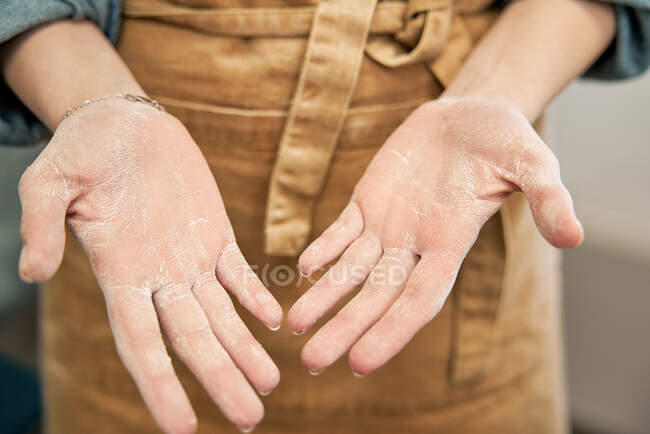 Ernte unkenntlich weiblich in Schürze zeigt Handflächen mit Mehl nach dem Kochen im Haus — Stockfoto