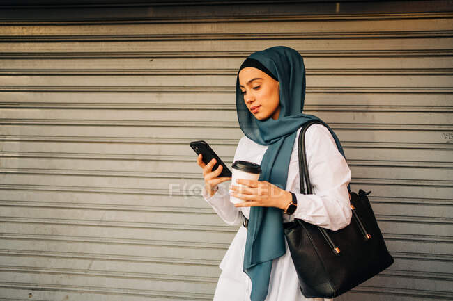 Ethnic female in hijab standing on street near closed shop — Stock Photo