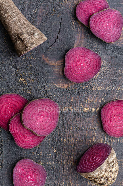Overhead composition of organic natural beetroot cut into slices and arranged on shabby wooden surface — Stock Photo