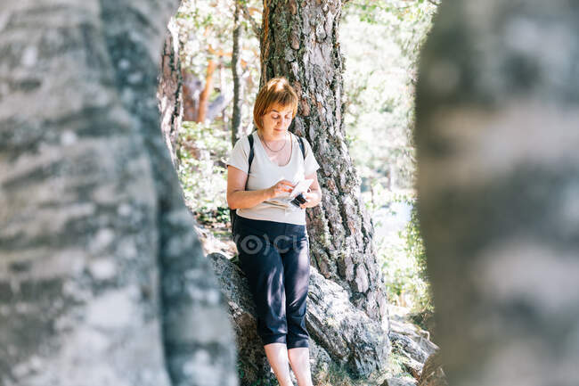 Maduro caminhante mensagens de texto feminino no celular entre árvores em florestas do Vale de Aran, na Lleida Catalunha Espanha — Fotografia de Stock
