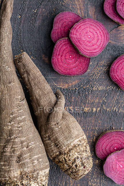 Overhead composition of organic natural beetroot cut into slices and arranged on shabby wooden surface — Stock Photo