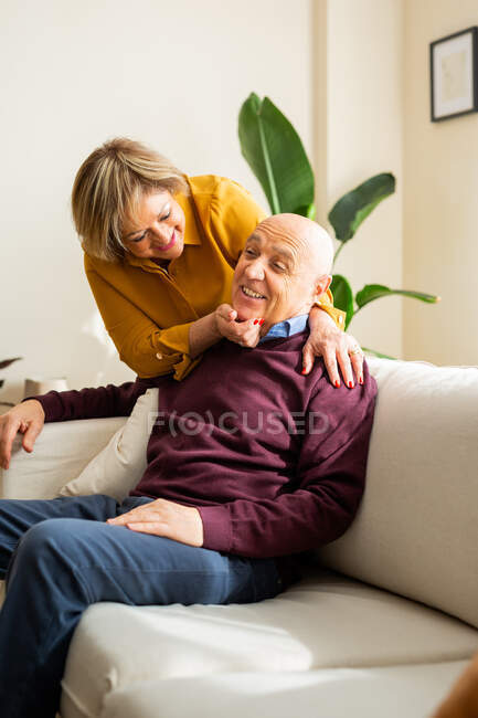 Positive middle aged couple having fun in living room while spending time together at home — Stock Photo
