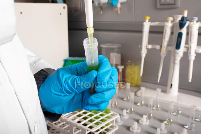 Crop chimiste anonyme verser de l'huile de marijuana de la pipette dans le tube à échantillon lors de l'examen en laboratoire — Photo de stock