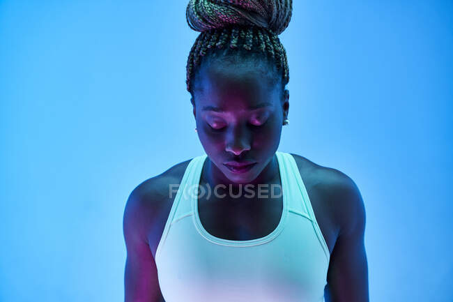 Jeune sportive afro-américaine avec des tresses afro en chignon et les yeux fermés sur fond bleu — Photo de stock