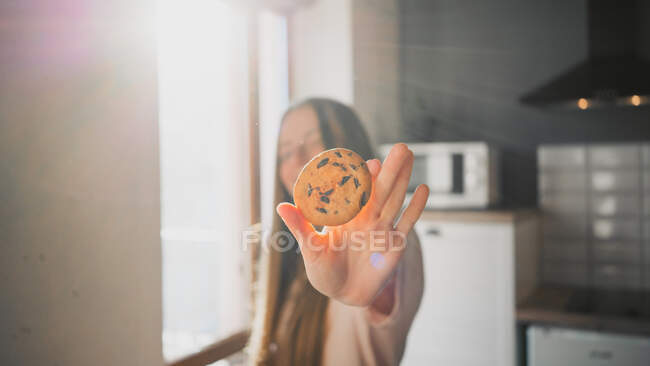 Молодая женщина с вкуснейшим овсяным печеньем с шоколадной крошкой дома в солнечный день — стоковое фото