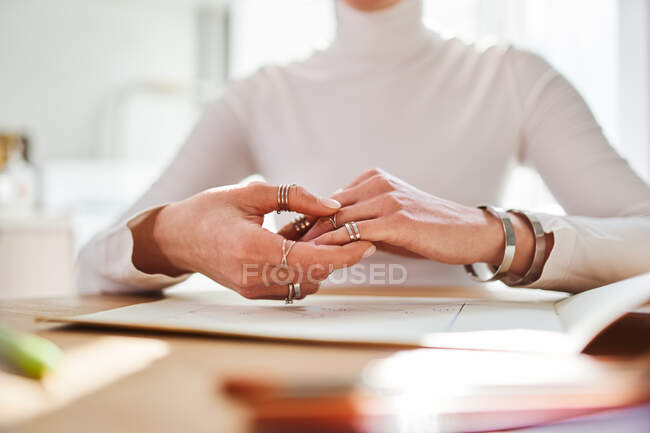 Crop astrologo femminile irriconoscibile in anelli e bracciali che lavorano alla scrivania con album di carta a casa — Foto stock
