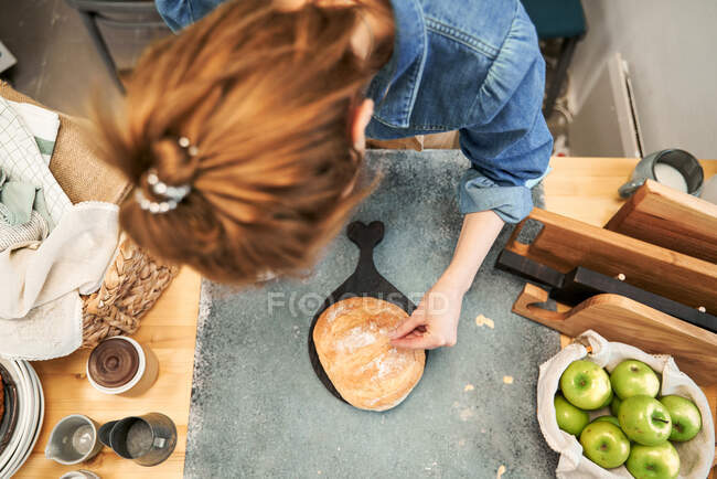 Alto angolo di anonima femmina cospargendo pane di grano con farina a tavola con mele fresche durante la cottura in casa — Foto stock
