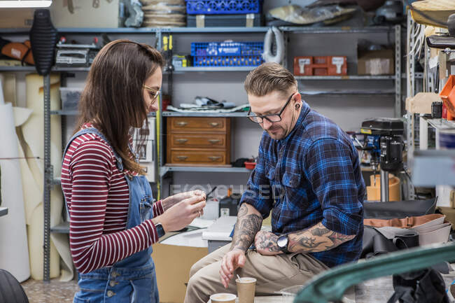 Seitenansicht eines Kunsthandwerkerpaares bei der Kaffeepause während der Arbeit in der Kreativwerkstatt — Stockfoto