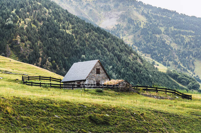 Сценічний вид на будівлі сільської місцевості на схилі пагорба між величними горами в долині Аран в Леїді Каталонії влітку. — стокове фото