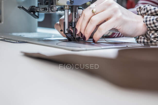 Kunsthandwerkerin schneidet mit Nähmaschine Polster für Motorradsitz in Werkstatt — Stockfoto