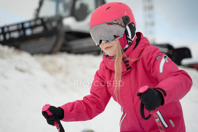 Positiv süßes Mädchen in pinkfarbener, warmer Activwear-Brille und Helm beim Skifahren entlang der verschneiten Piste an klaren Wintertagen — Stockfoto