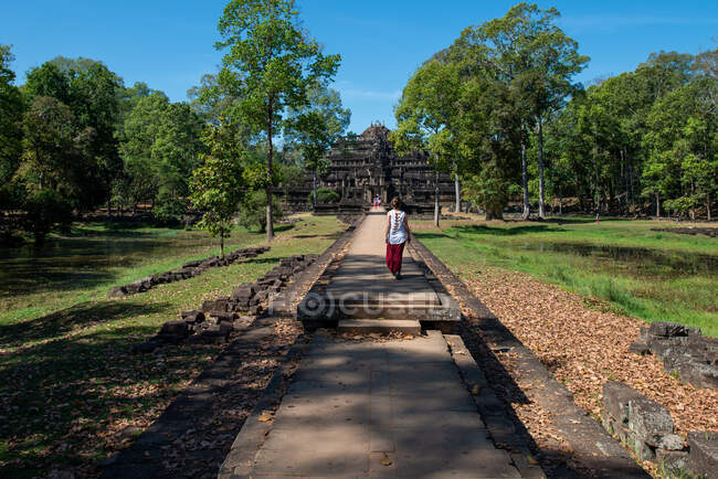 Back view of anonymous female tourist on footpath against aged stone temple facade in Angkor Wat of Cambodia — Stock Photo