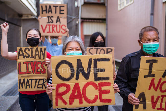 Attivisti etnici con le iscrizioni I Am Not A Virus e One Race sui cartelli durante il movimento Stop Asian Hate in città — Foto stock