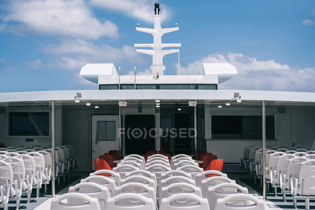 Deck of cruise boat with empty white chairs in row under clear sky with clouds — Stock Photo