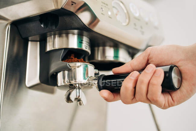 Обрізати невпізнавану людину, що вставляє портативний фільтр з меленою кавою в сучасний виробник еспресо в будинку — стокове фото