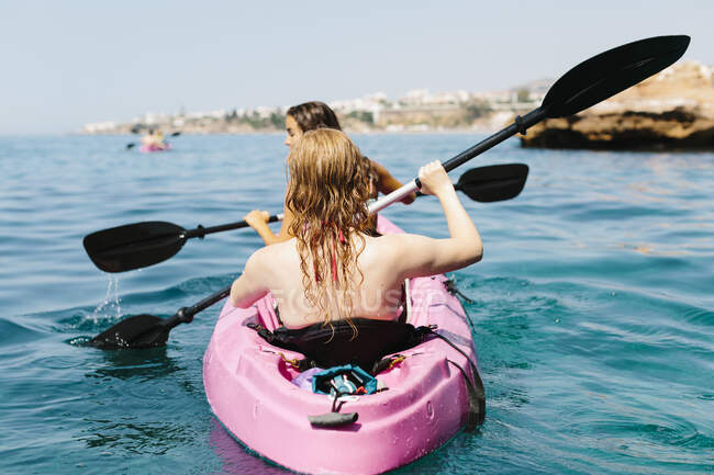 Просмотр путешественников с веслами, плавающих на бирюзовой морской воде возле скалистого берега в солнечный день в Малаге Испания — стоковое фото