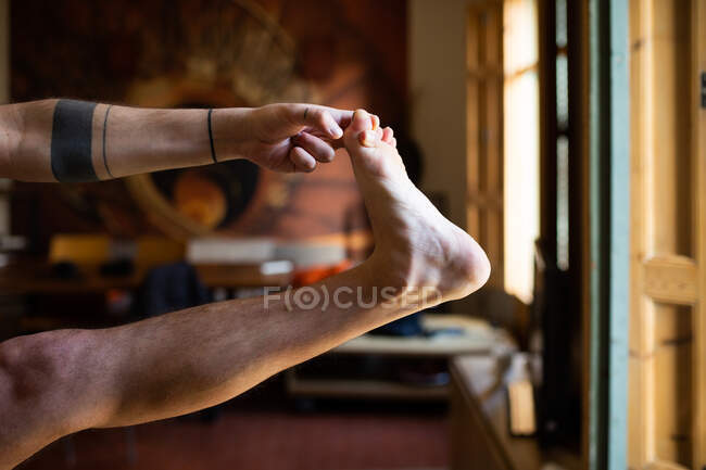 Crop unrecognizable flexible male balancing in Hasta Padangusthasana while practicing yoga at home — Stock Photo