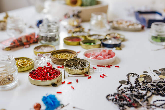 Vue latérale de diverses perles de clairon décoratives dans des conteneurs métalliques sur une table en bois — Photo de stock