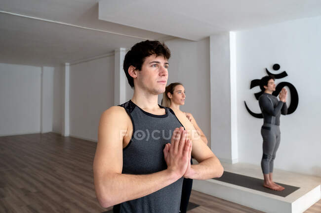 Maschio sereno in abbigliamento sportivo in piedi in montagna con le mani di preghiera posa e fare yoga durante la lezione in studio — Foto stock