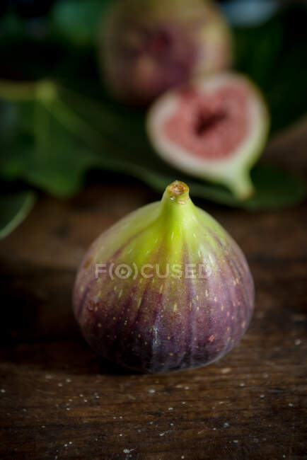 Whole fig with juicy pulp on wooden surface — Stock Photo