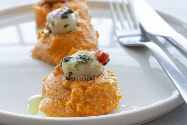 Сверху вкусные гребешки с вкусным сладким картофельным пюре на белой тарелке на столе — стоковое фото