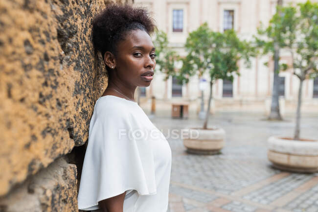 Portrait of attractive African American female standing in historic city district on warm spring day and looking at camera — Stock Photo