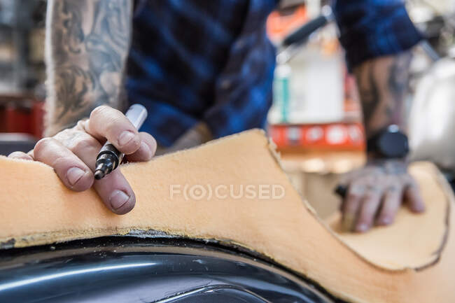 Artisan de culture utilisant du caoutchouc mousse pour créer un siège de moto à la main dans l'atelier — Photo de stock