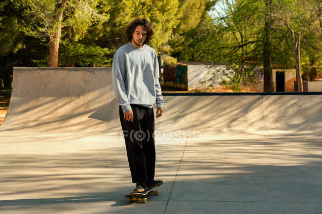 Joven montando un monopatín en skatepark urbano - foto de stock