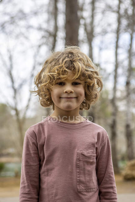 Charmantes Kind in weicher grauer Kleidung, das im Freien auf verschwommenem Hintergrund in die Kamera blickt — Stockfoto