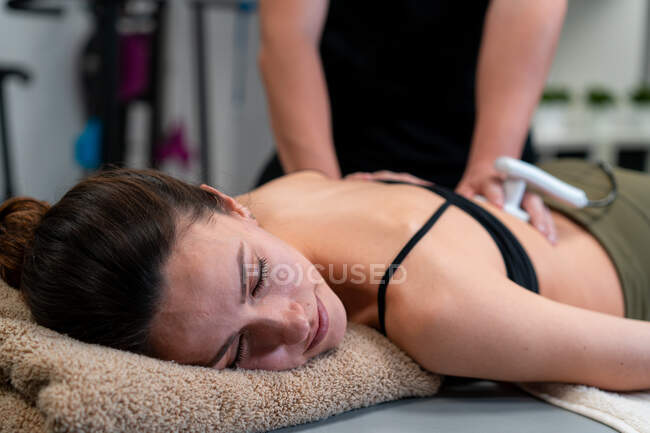 Male physiotherapist applying laser to back skin of female during medical treatment in hospital — Stock Photo