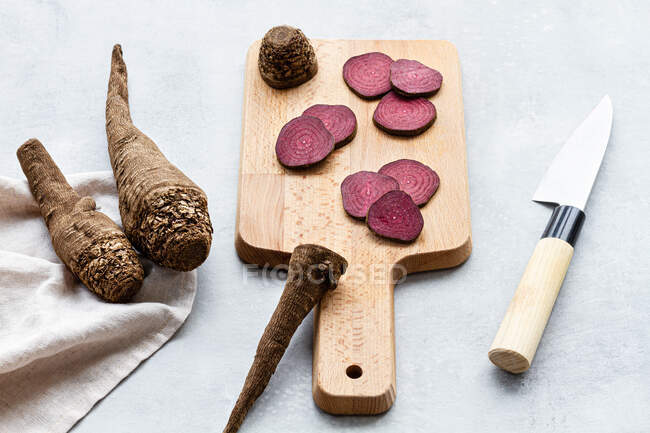From above composition of ripe raw beetroot slices placed on wooden cutting board on kitchen table near sharp knife — Stock Photo