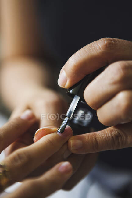 Crop unrecognizable master applying polish on nails of anonymous client in beauty salon — Stock Photo