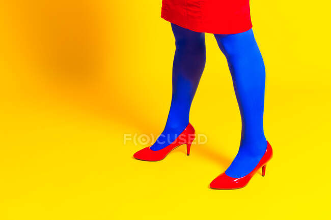 Side view of crop unrecognizable female model wearing bright shoes and pantyhose in vivid studio — Stock Photo