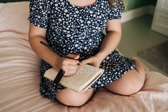 Беременная женщина сидит на кровати и пишет заметки. — стоковое фото